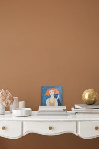 Small Figurative artwork sitting on a desk with a stack of books  